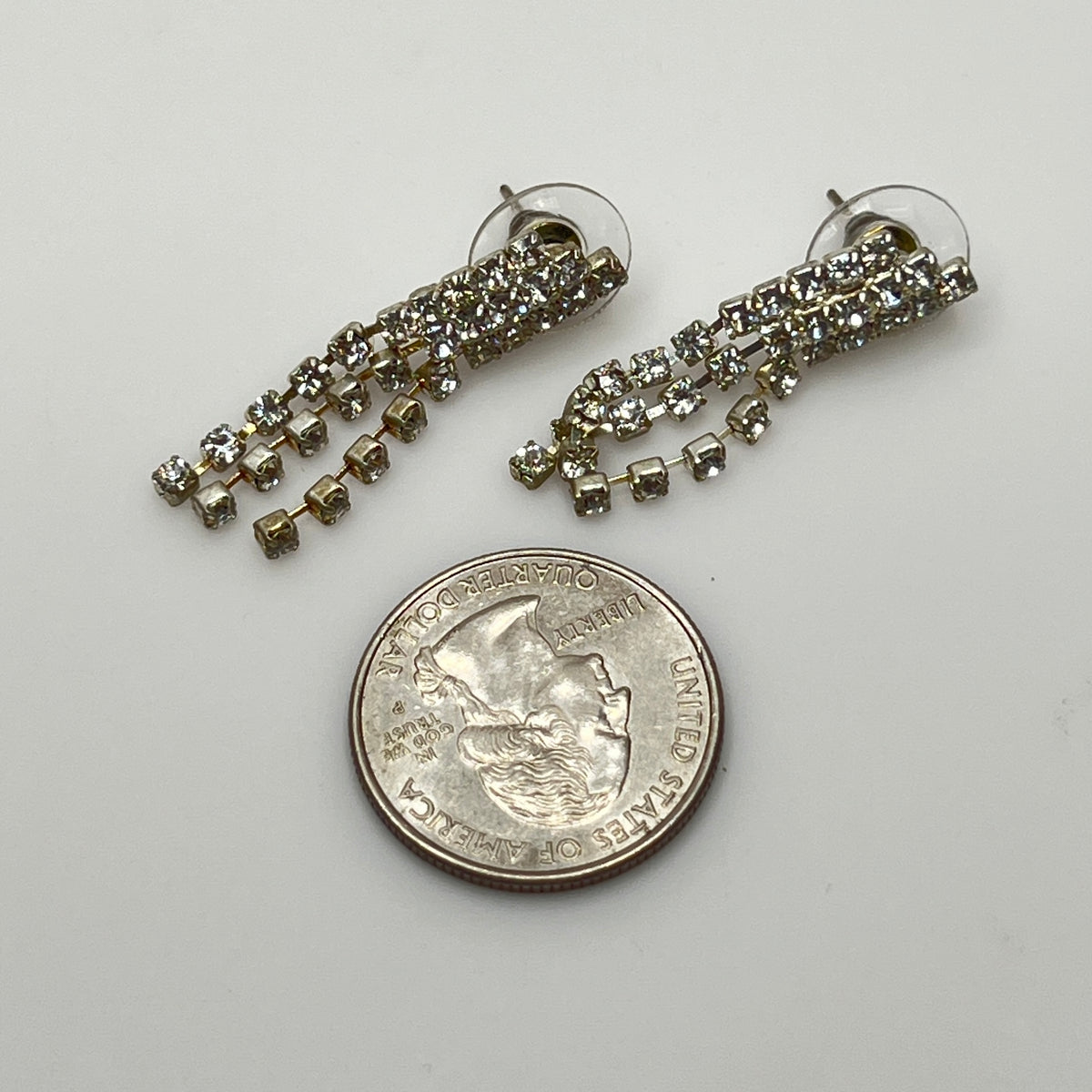 Close-up of silver-tone fringe earrings with prong-set crystals