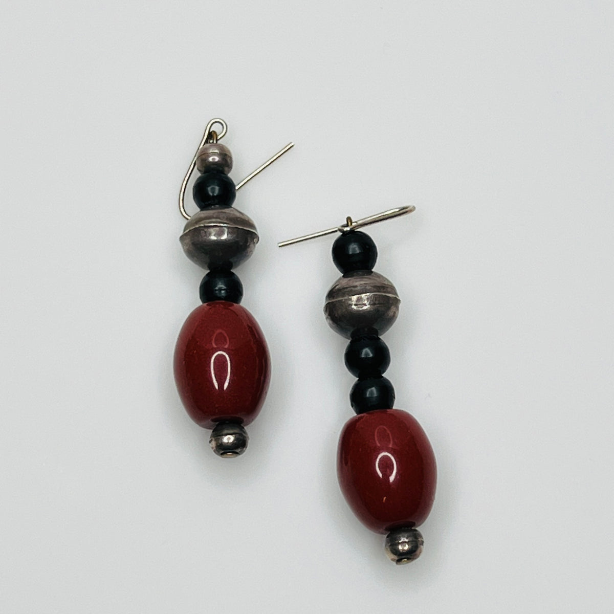 Pair of earrings with red, black, and silver beads on a white background