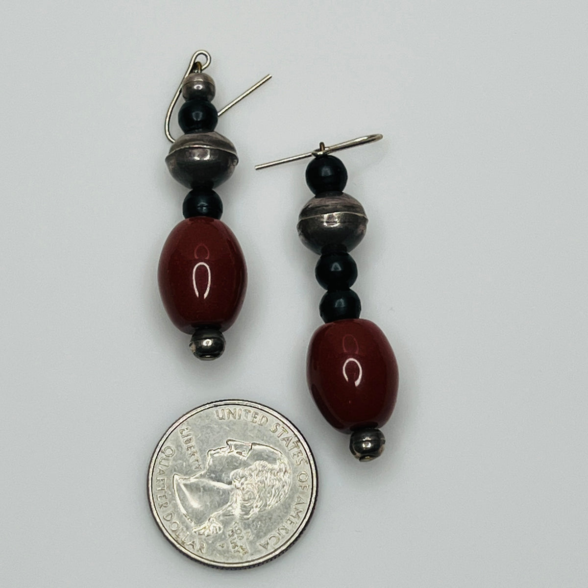 Pair of beaded earrings with a quarter for scale on a gray background