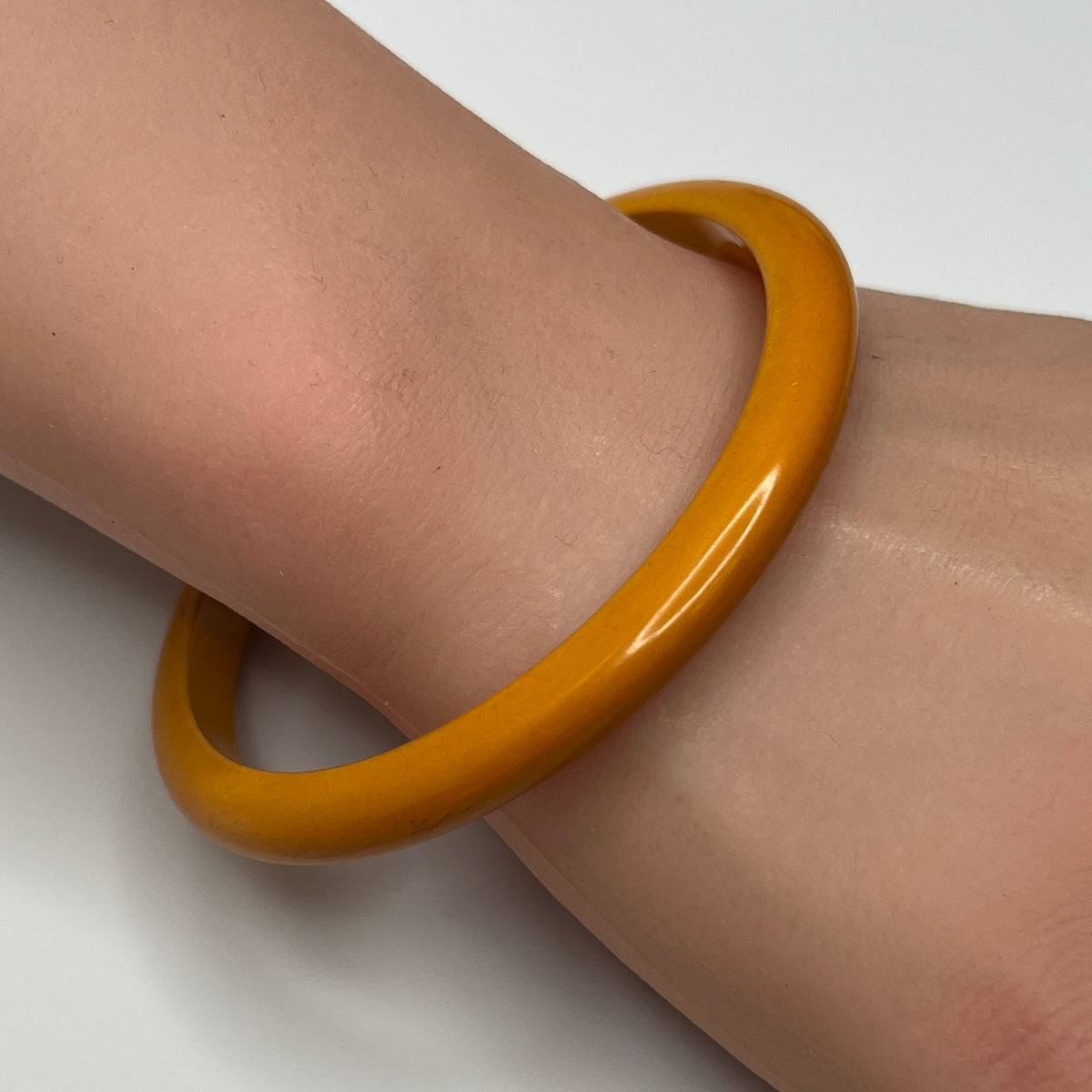 Butterscotch Bakelite bangle bracelet on wrist, slim vintage style