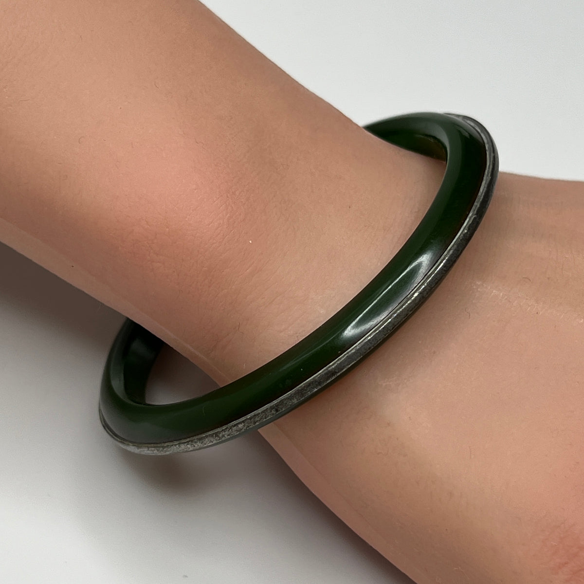 Vintage Bakelite bracelet on wrist showing glossy finish and silver channel