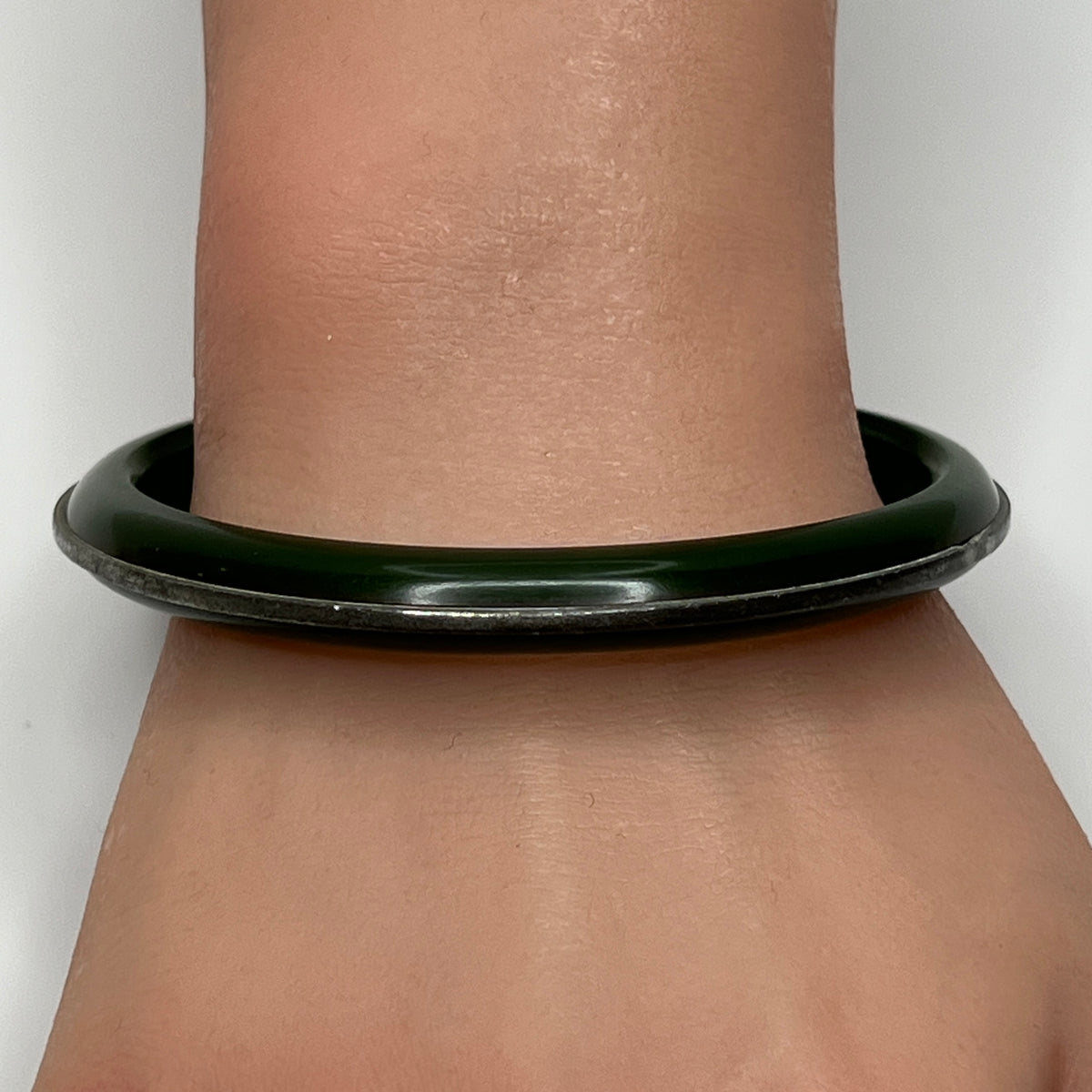 Vintage Bakelite bracelet on wrist showing glossy finish and silver channel