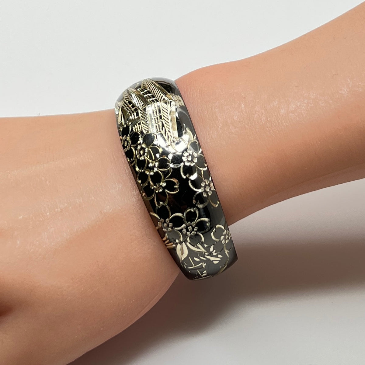 Bracelet shown on wrist, highlighting engraved silver pagoda and blossoms