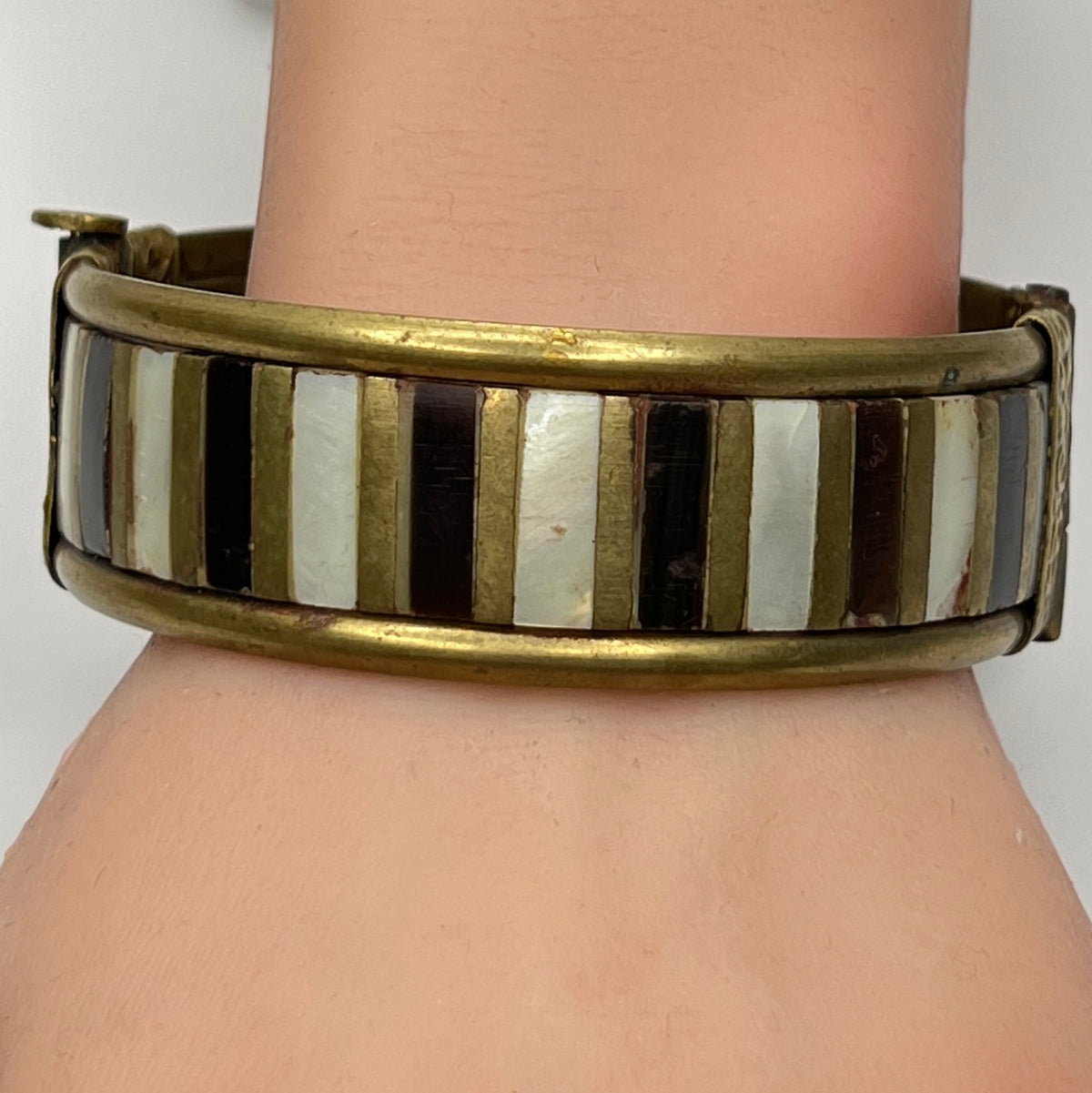 Rustic brass and mother of pearl artisan bangle worn on mannequin