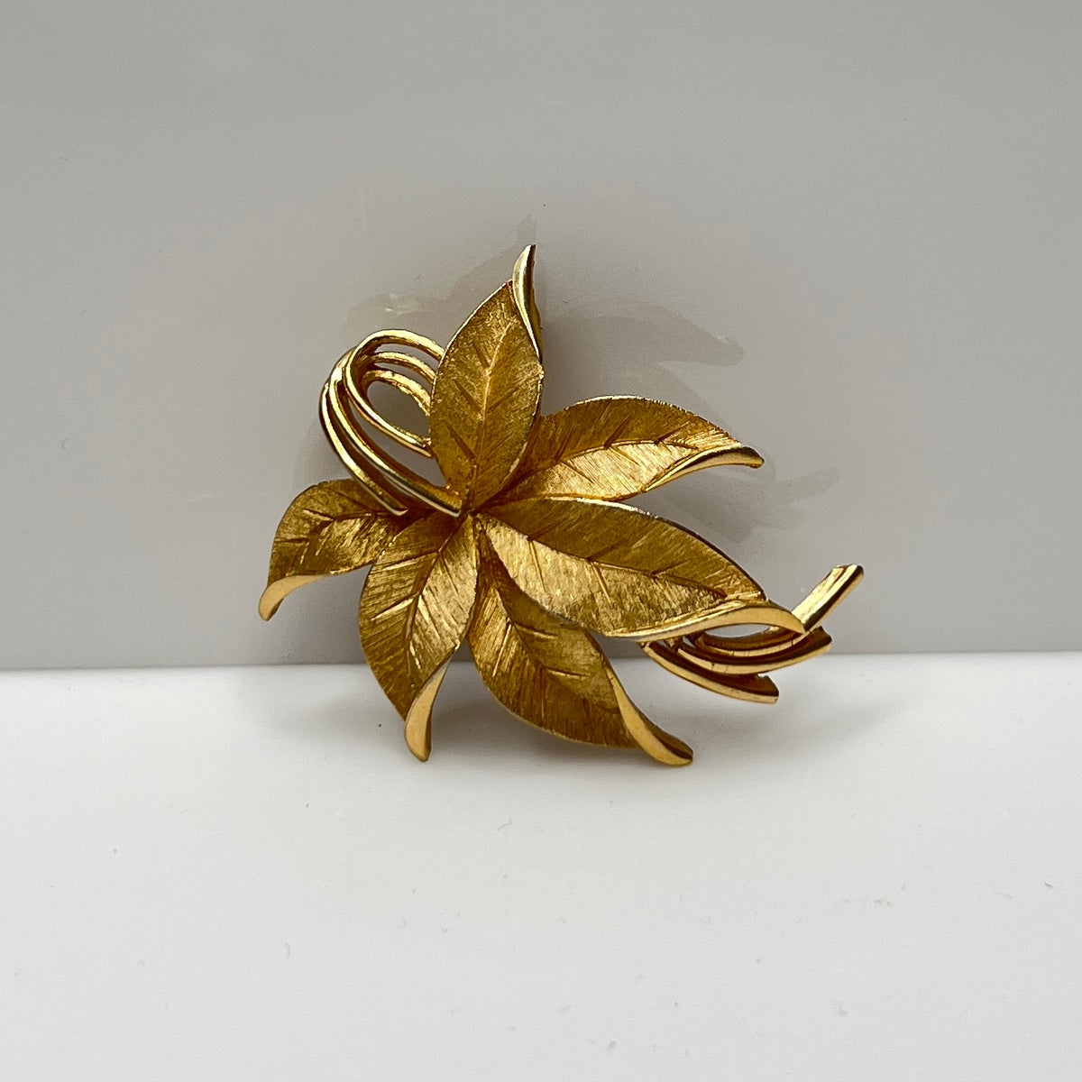 Crown Trifari brushed gold-tone leaf brooch with curling ribbon detail