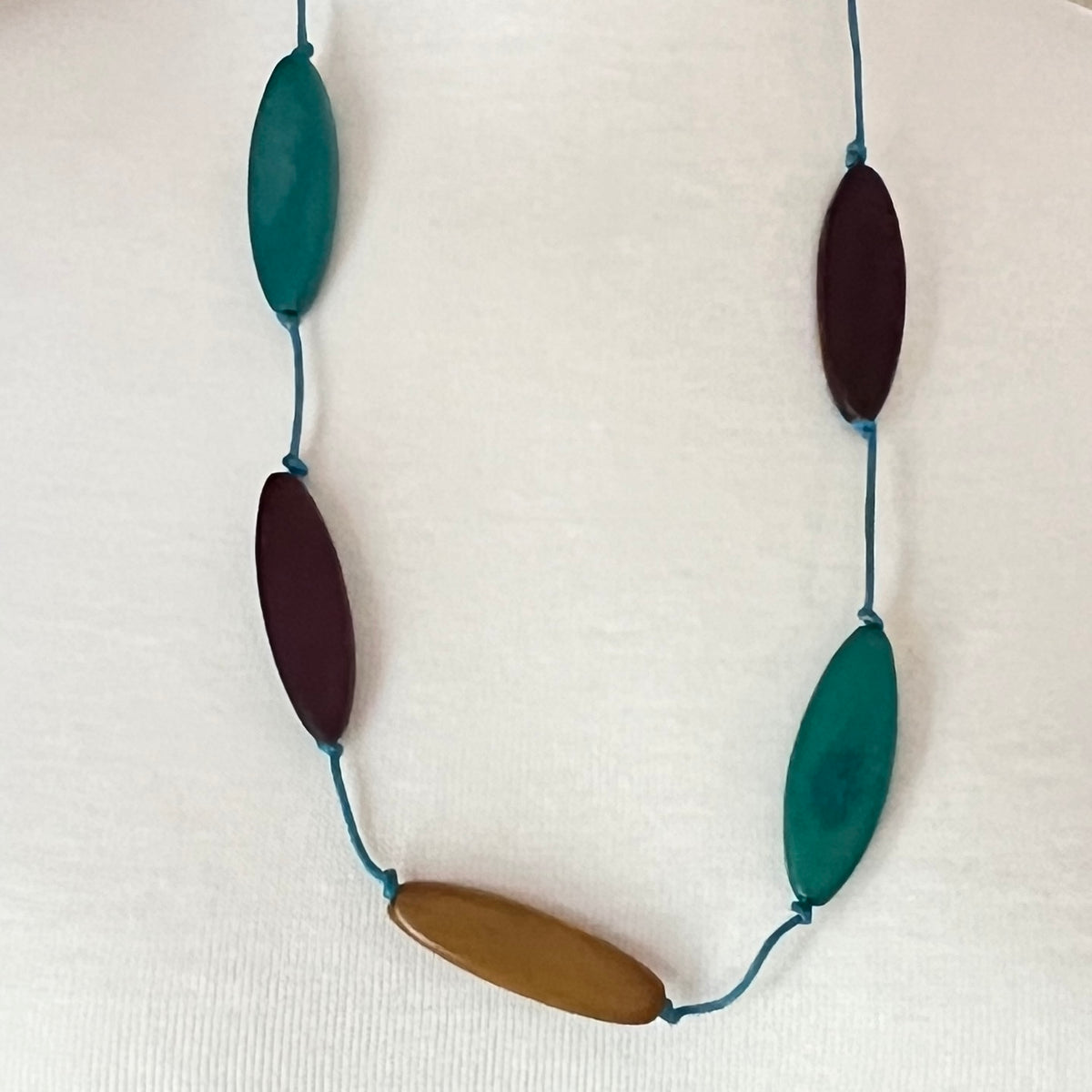 Harry Haslett Island Design necklace with long oval wood beads in teal, plum, and mustard on turquoise cord.