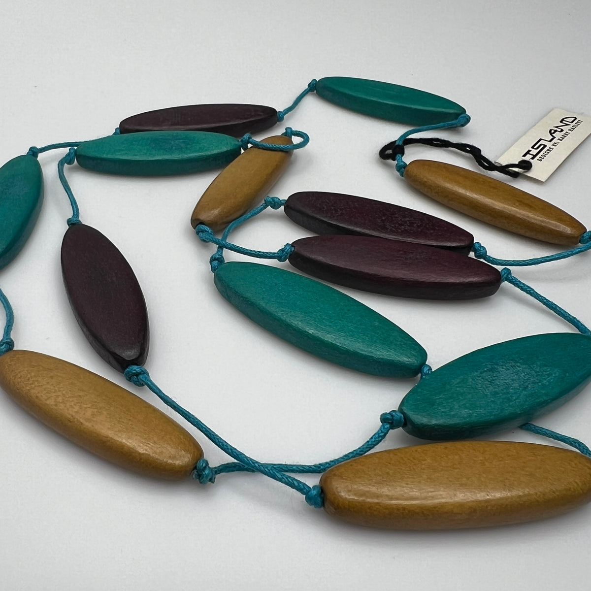 Harry Haslett Island Design necklace with long oval wood beads in teal, plum, and mustard on turquoise cord.