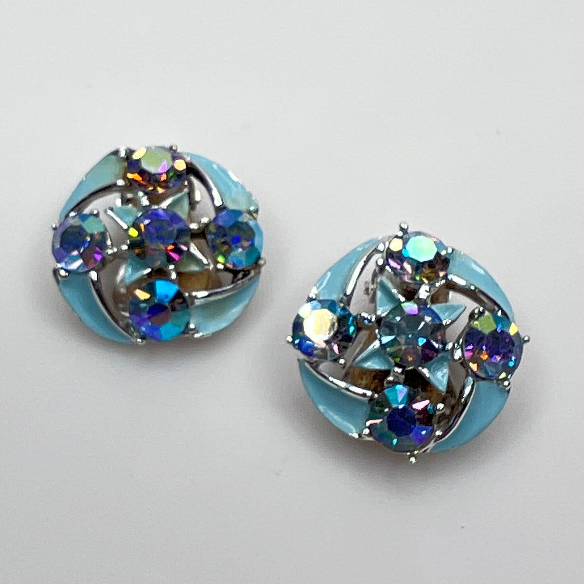 Close-up of round rhinestone earrings with blue enamel petals
