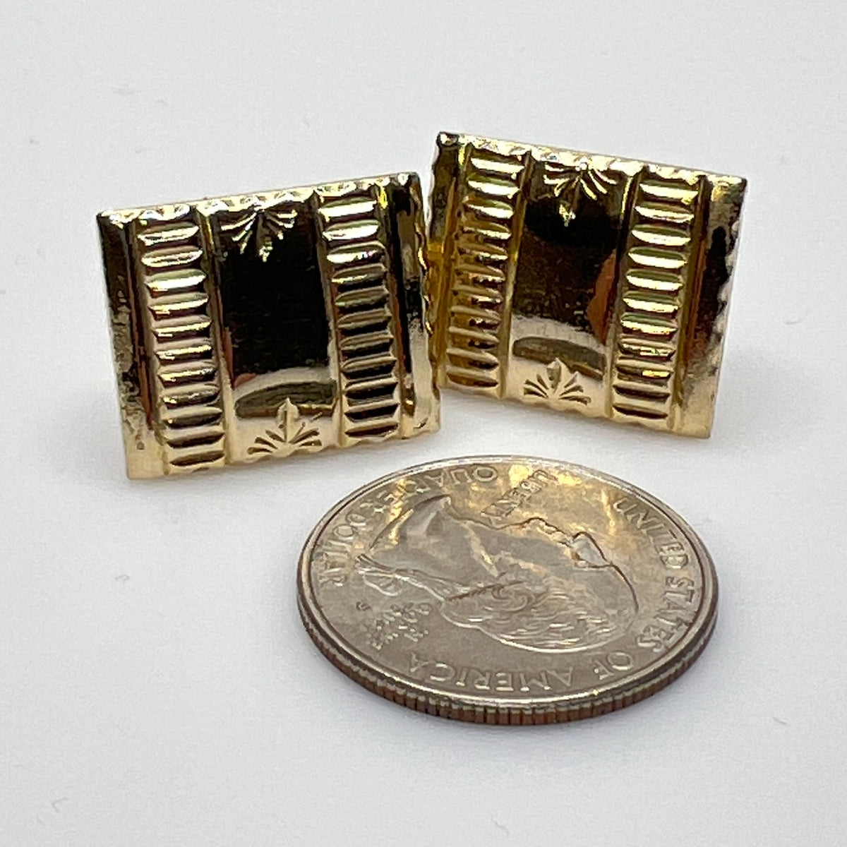 Close-up of 1930s gold cufflinks next to U.S. quarter for scale