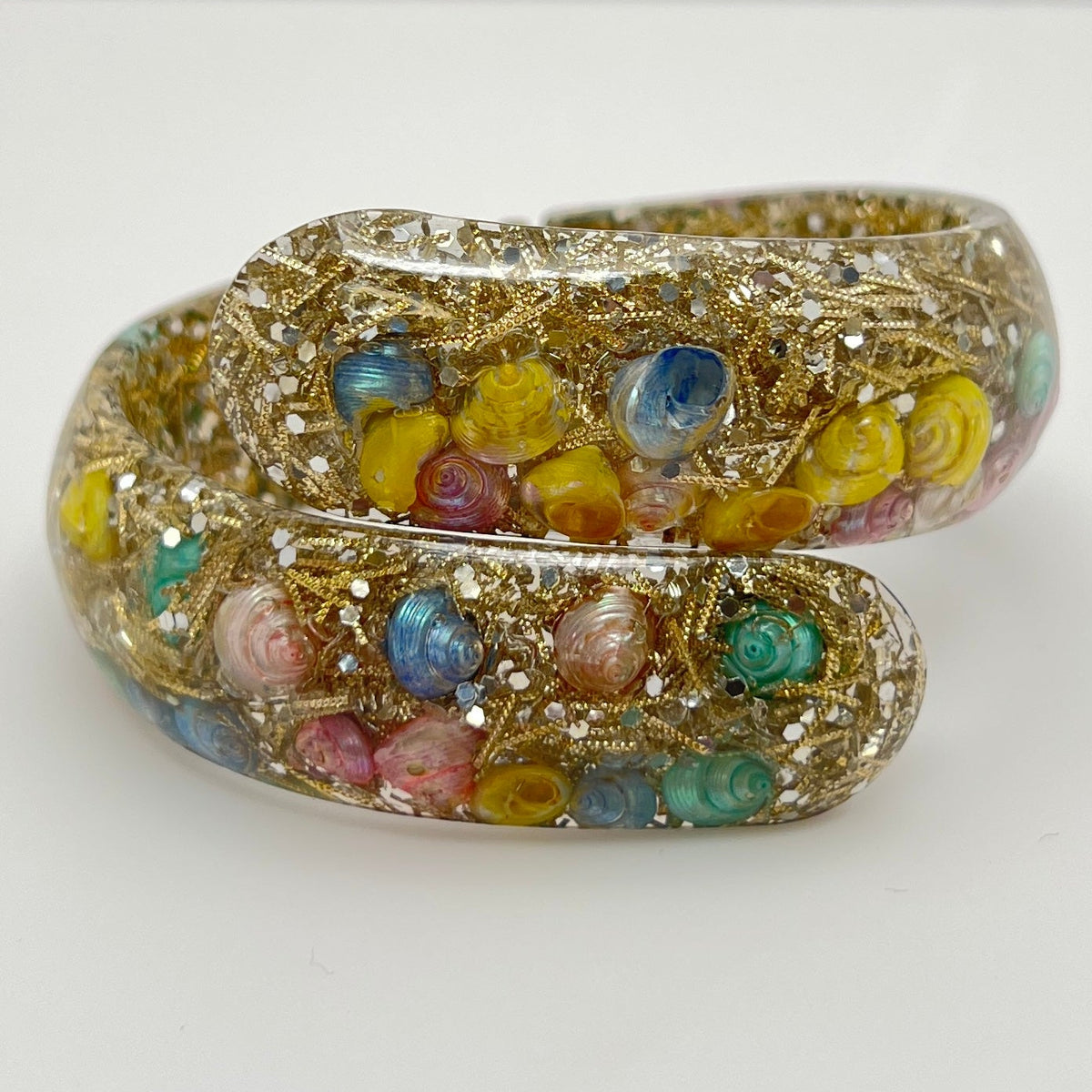 Vintage hinged bracelet with colorful shells suspended in clear lucite