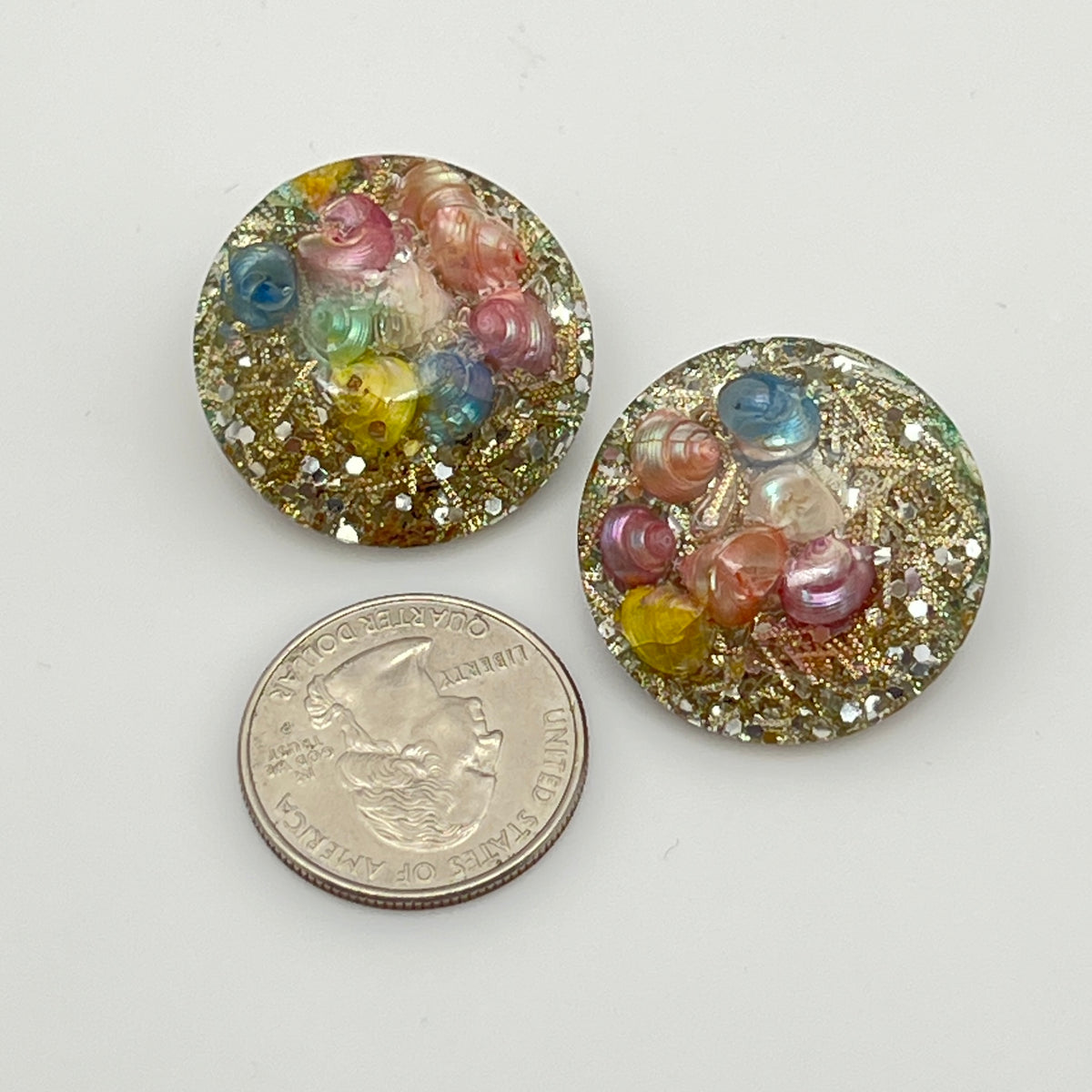 Close-up of lucite earrings with multicolor seashells and gold sparkle
