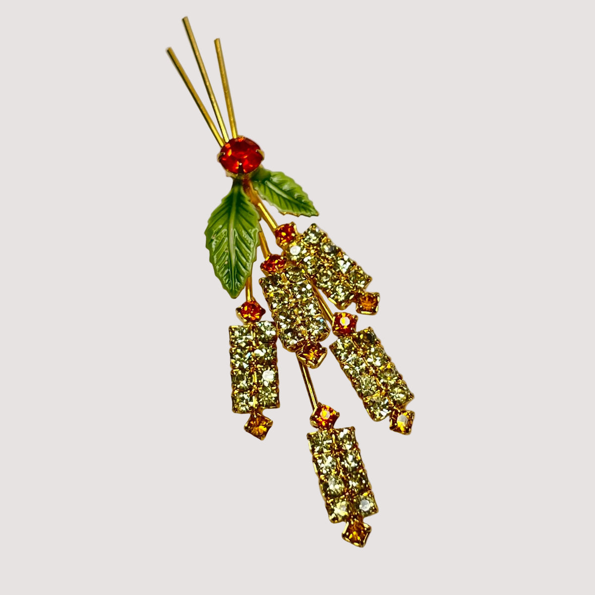Decorative brooch with gemstones and leaves on a light gray background