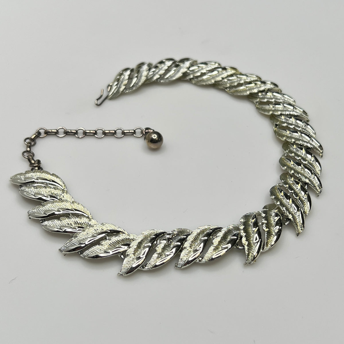 Mid-century silver-tone choker necklace with sculpted leaf links and hook extender clasp.