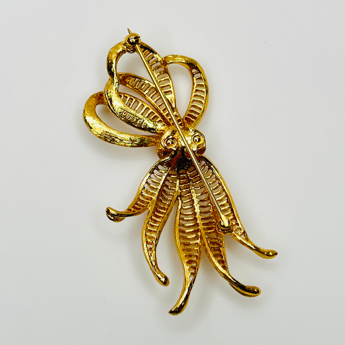 back view of dimensional gold ribbon brooch with textured detailing