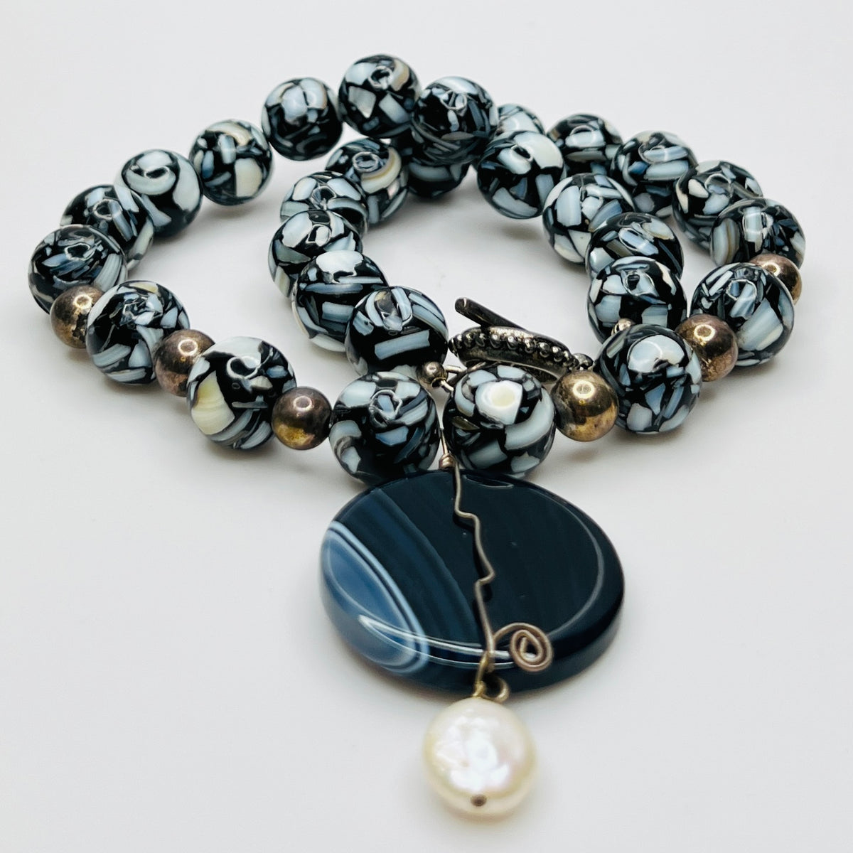 Centered view of striped agate pendant with pearl drop