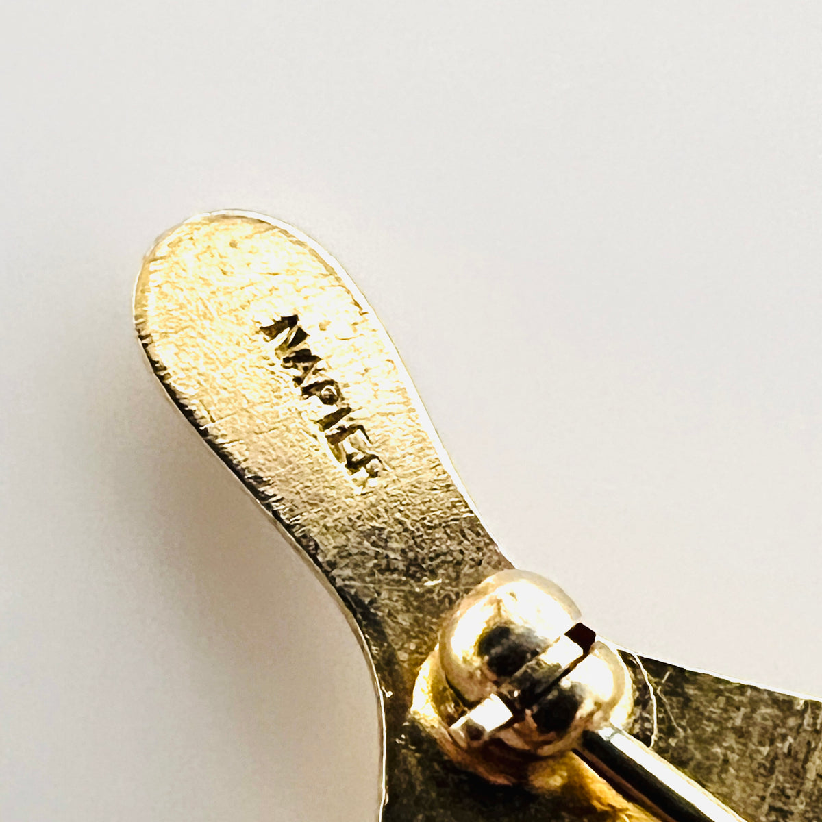 Close-up of the Napier signature stamped on the reverse of the gold-tone wishbone brooch.