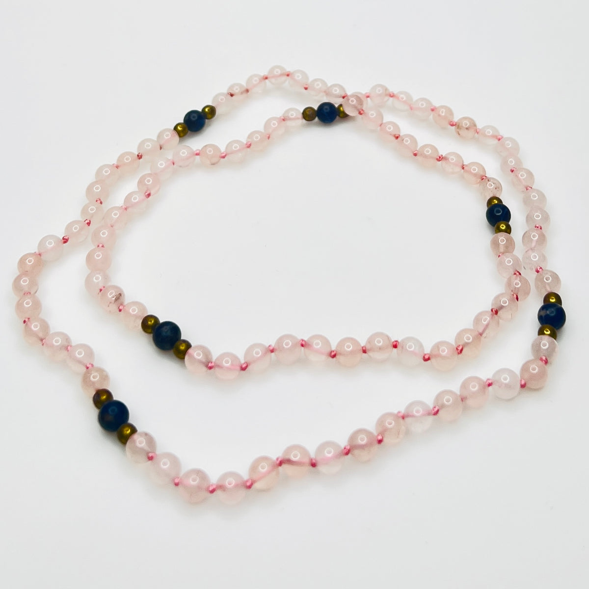 Long artisan rose quartz necklace on display form