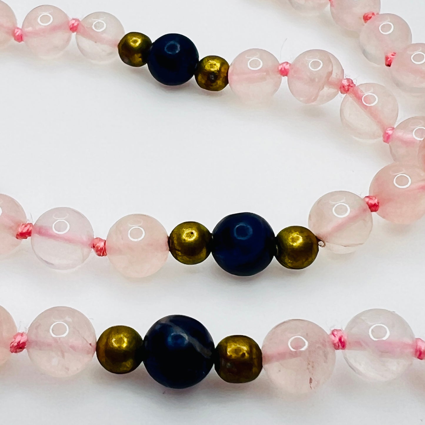 Close up of lapis and brass spacer beads with pink knotting