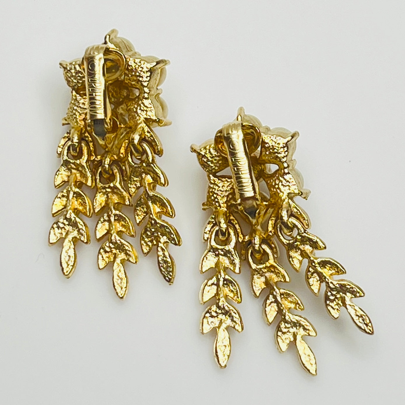 Pair of gold leaf earrings on a light gray background