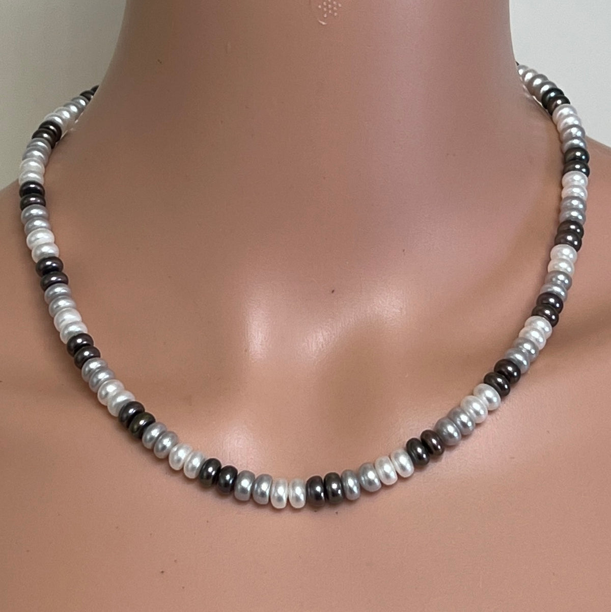 Tri-color cultured pearl necklace worn on mannequin with alternating white, grey, and black pearls
