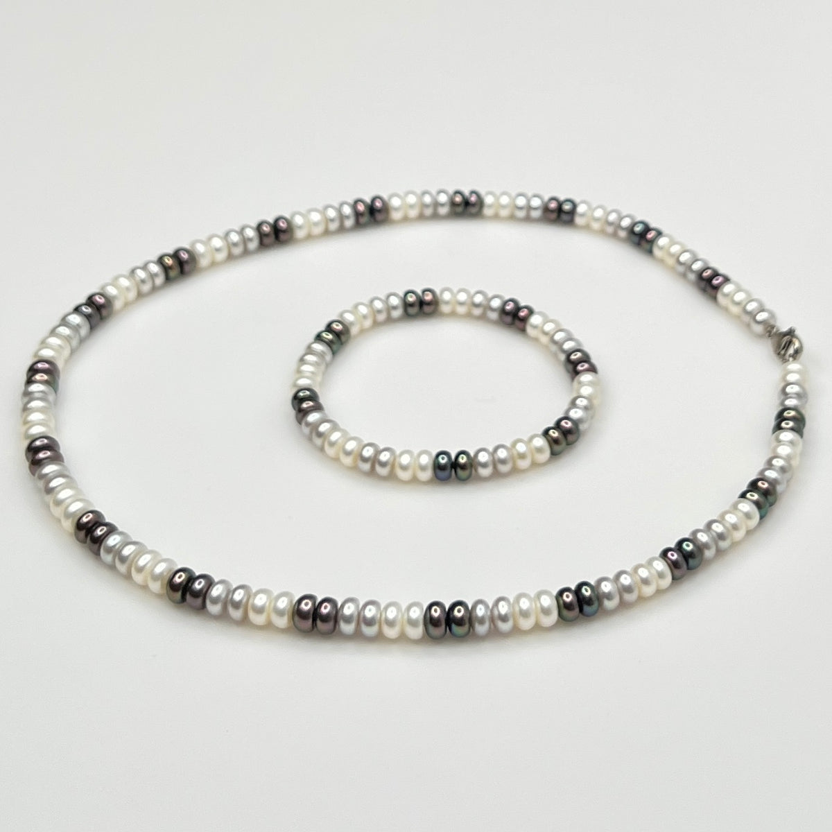 Close-up of matching pearl necklace and stretch bracelet in modern neutral tones