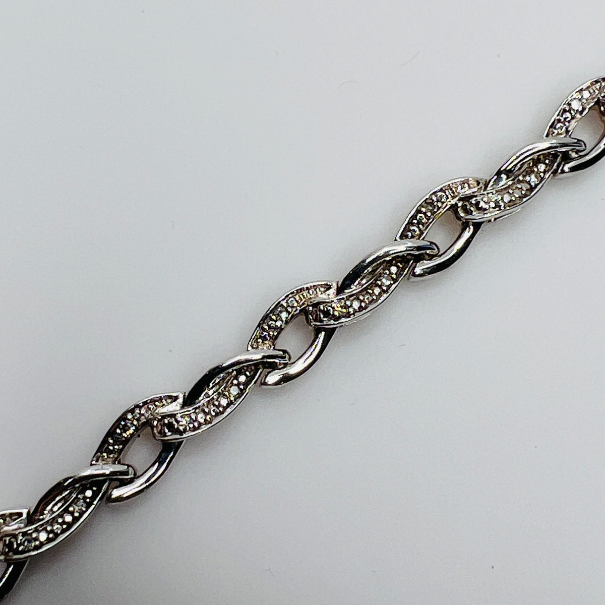 Close-up of diamond-accented links with prong and textured settings