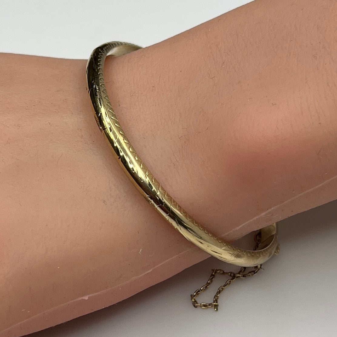 Gold vermeil etched bangle bracelet on wrist with floral design