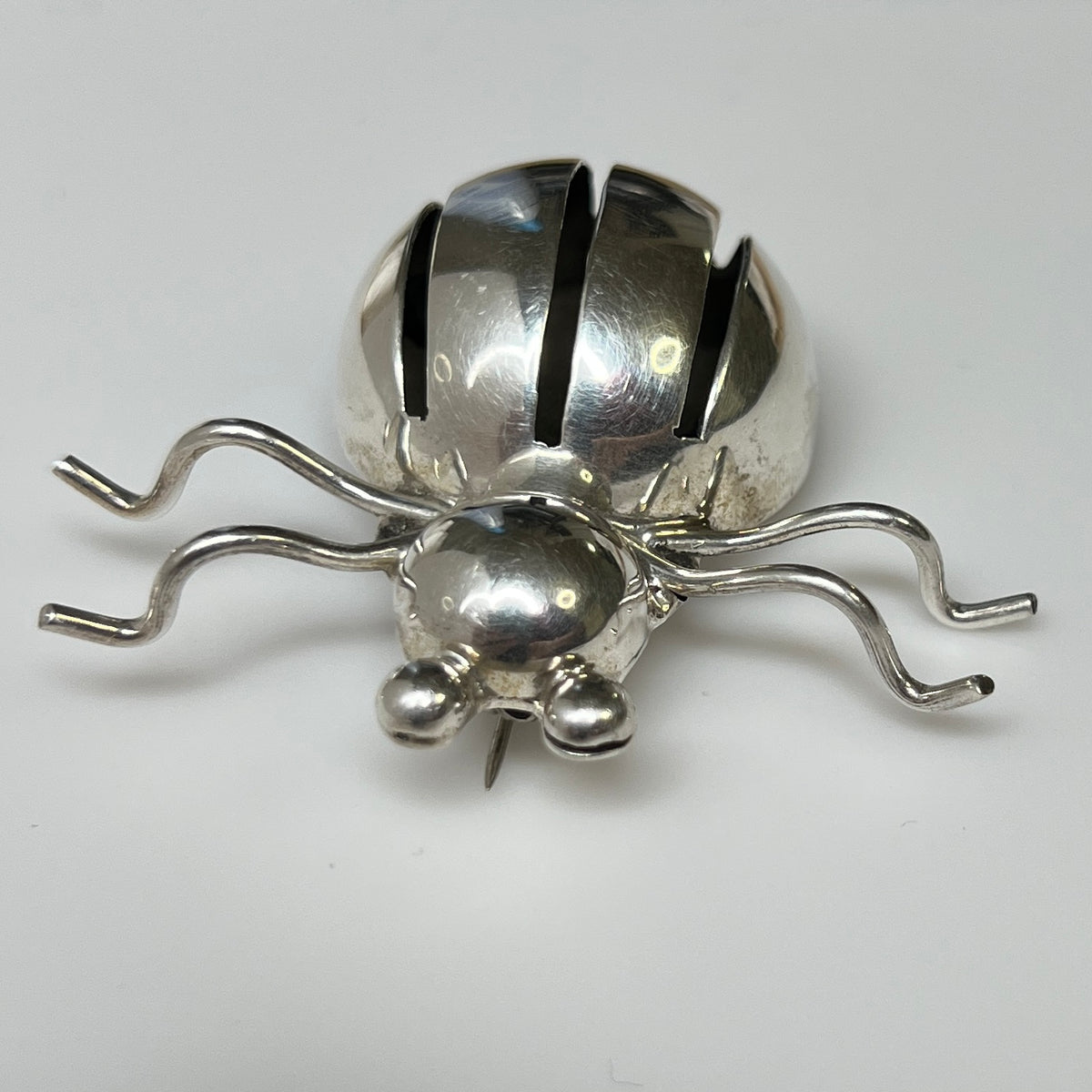 Sterling silver spider brooch with stylized body and curved legs