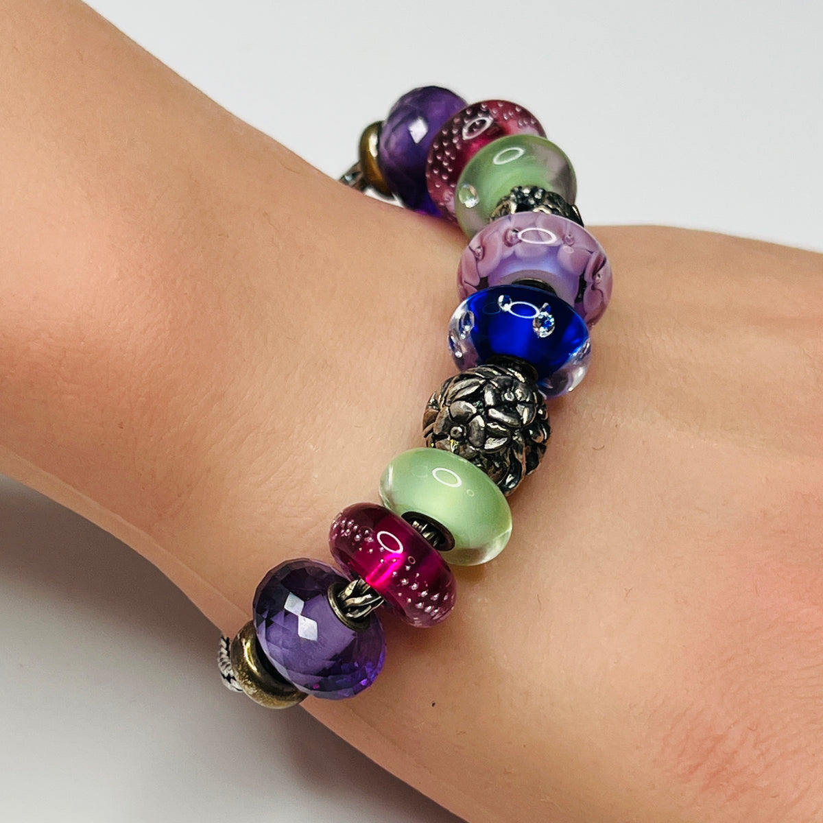 Close-up of sterling silver and glass charm bracelet with multicolored beads