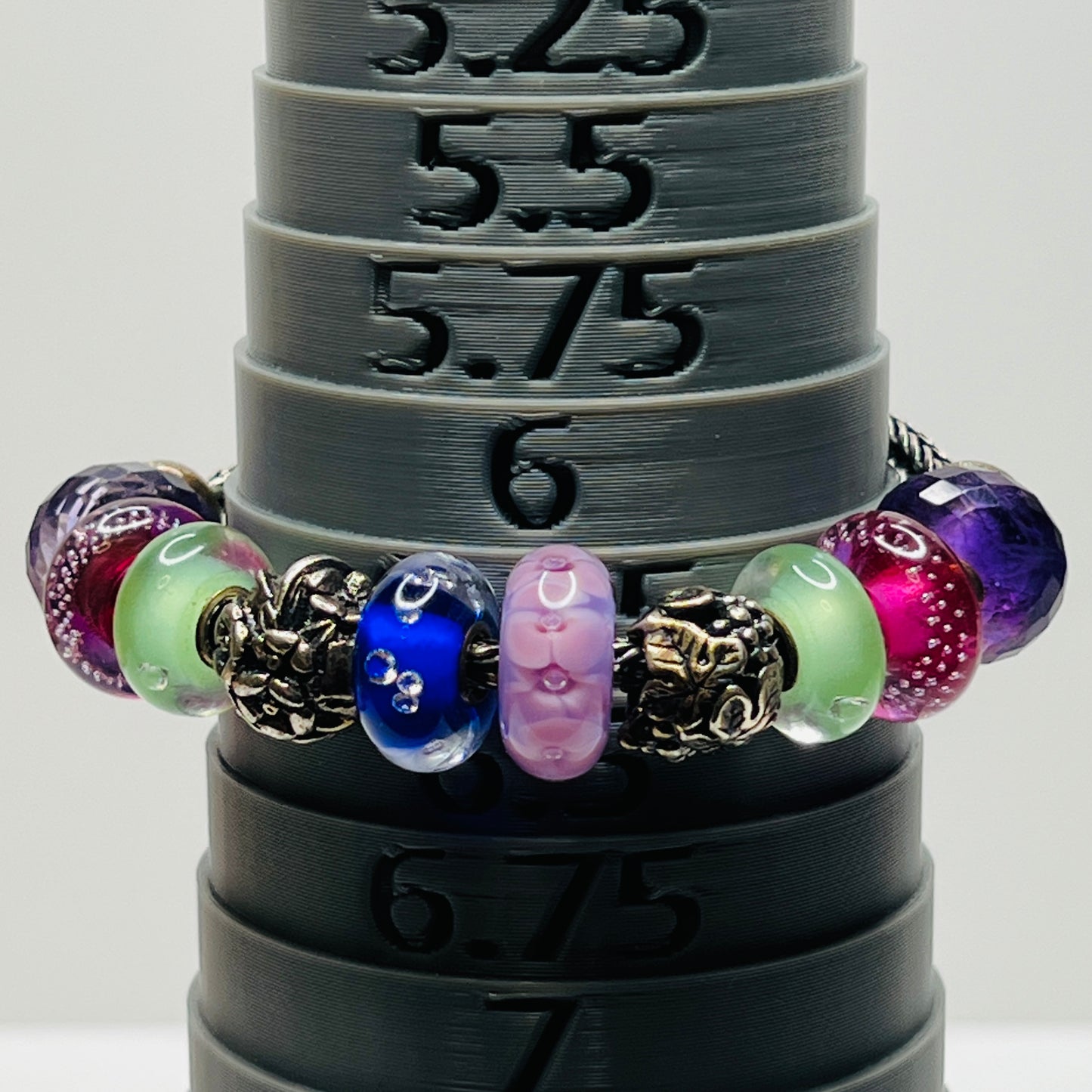 Close-up of sterling silver and glass charm bracelet with multicolored beads