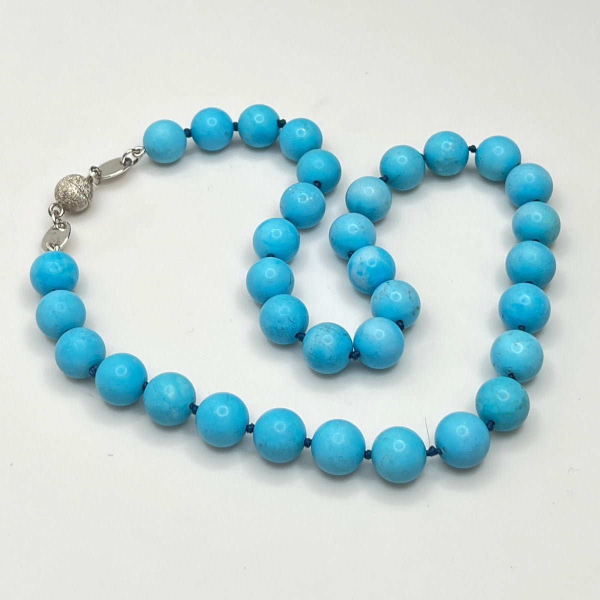 Close-up of turquoise beads with sterling magnetic clasp, laid flat
