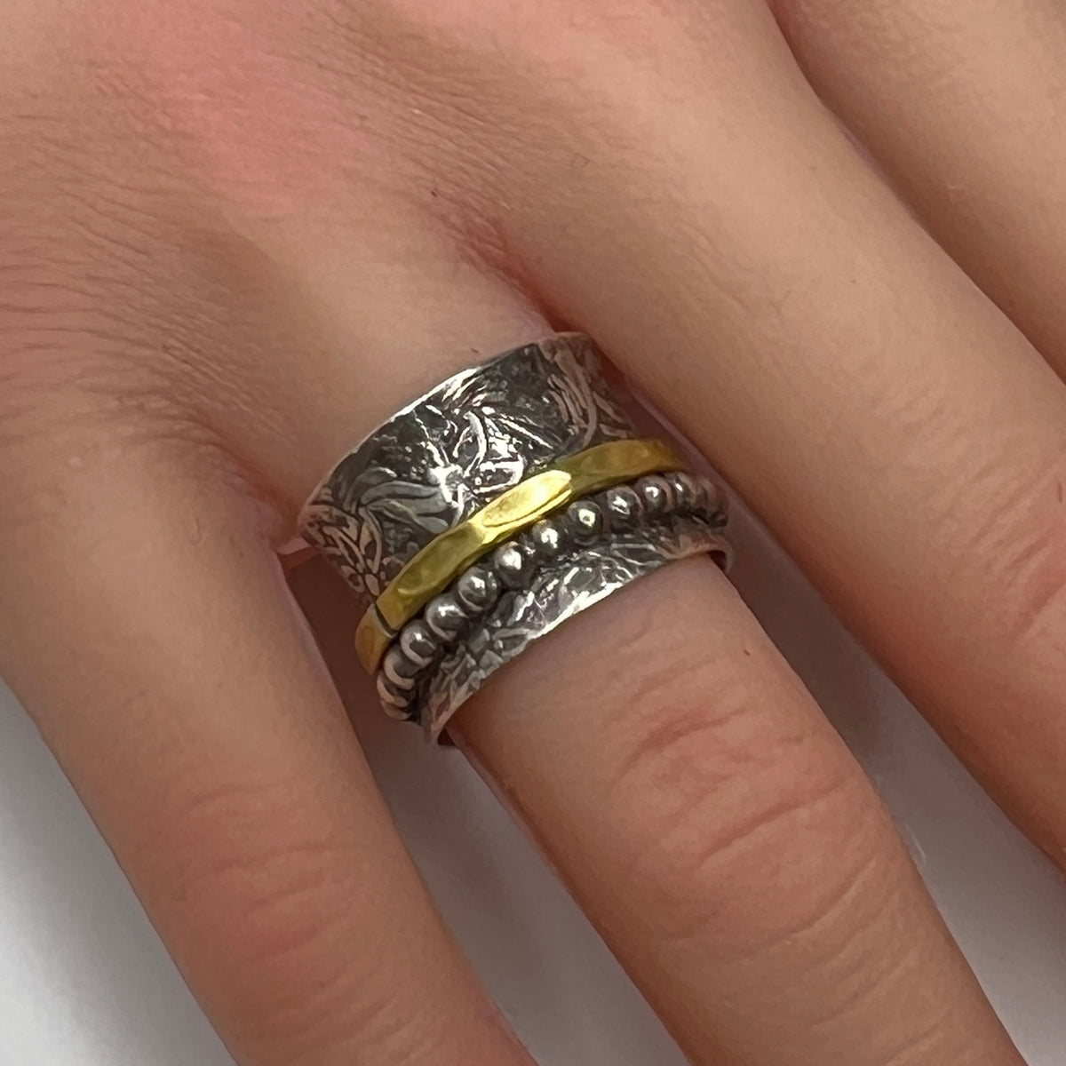 Close-up of oxidized silver ring on hand, showcasing spinning bands and textured detail