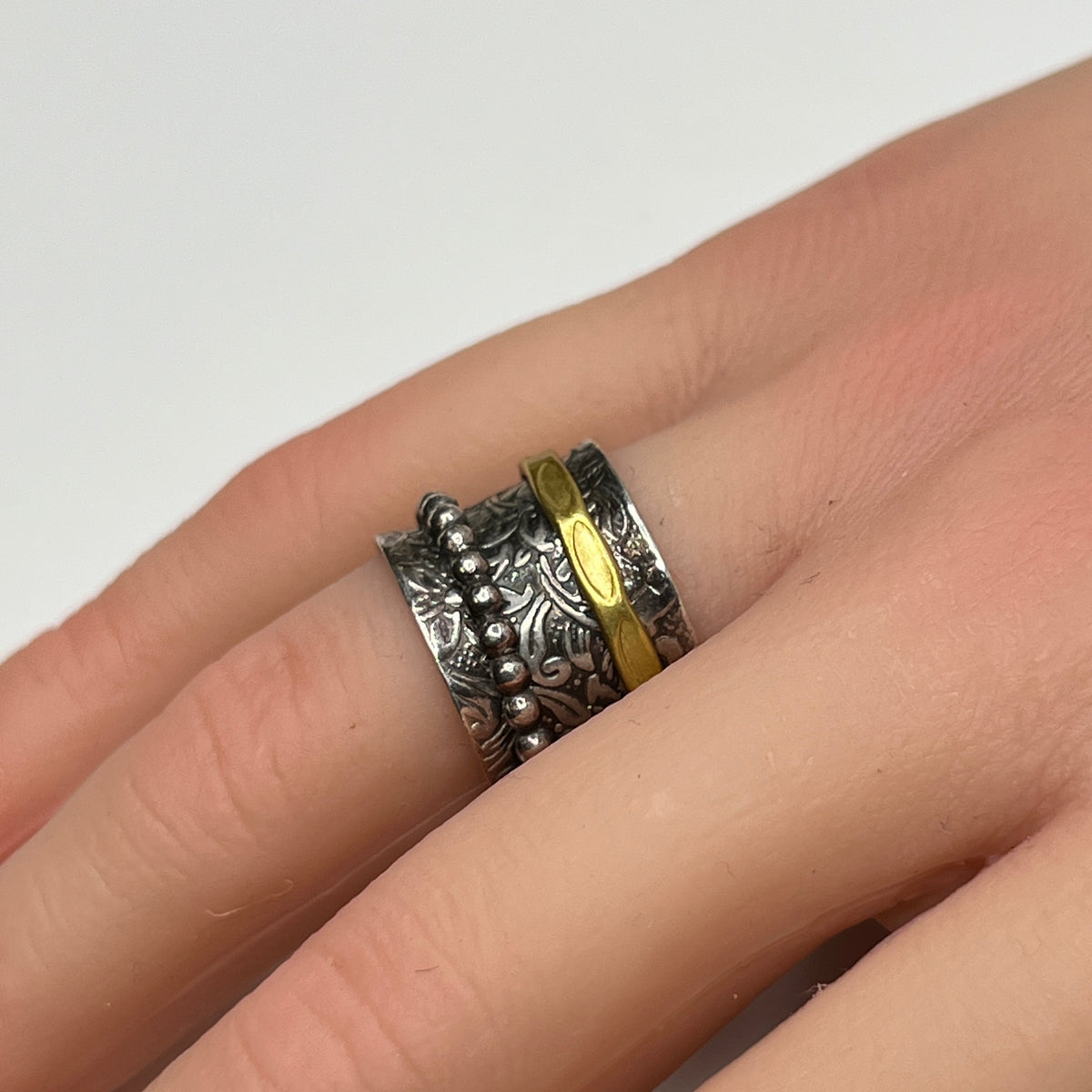 Close-up of oxidized silver ring on hand, showcasing spinning bands and textured detail