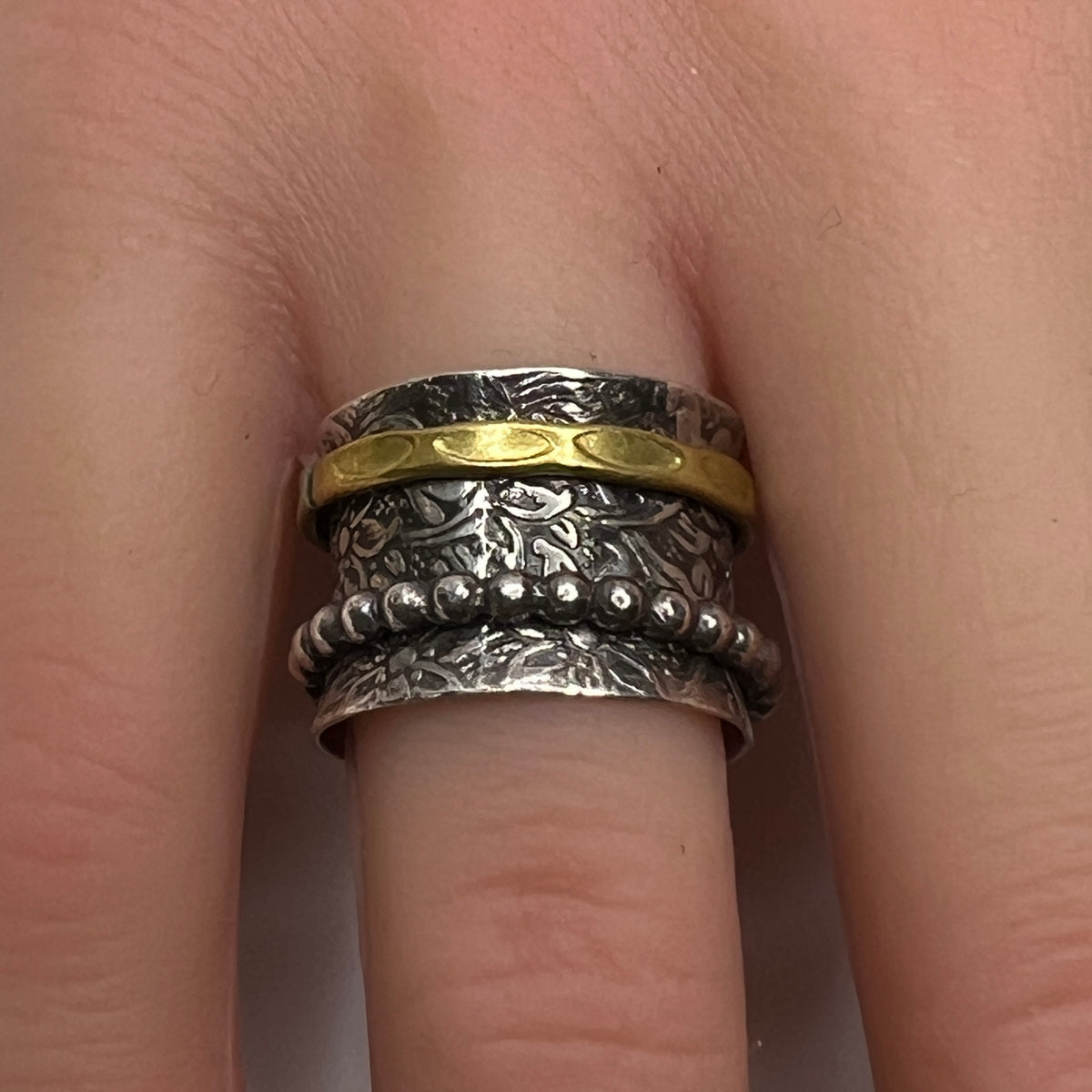 Close-up of oxidized silver ring on hand, showcasing spinning bands and textured detail