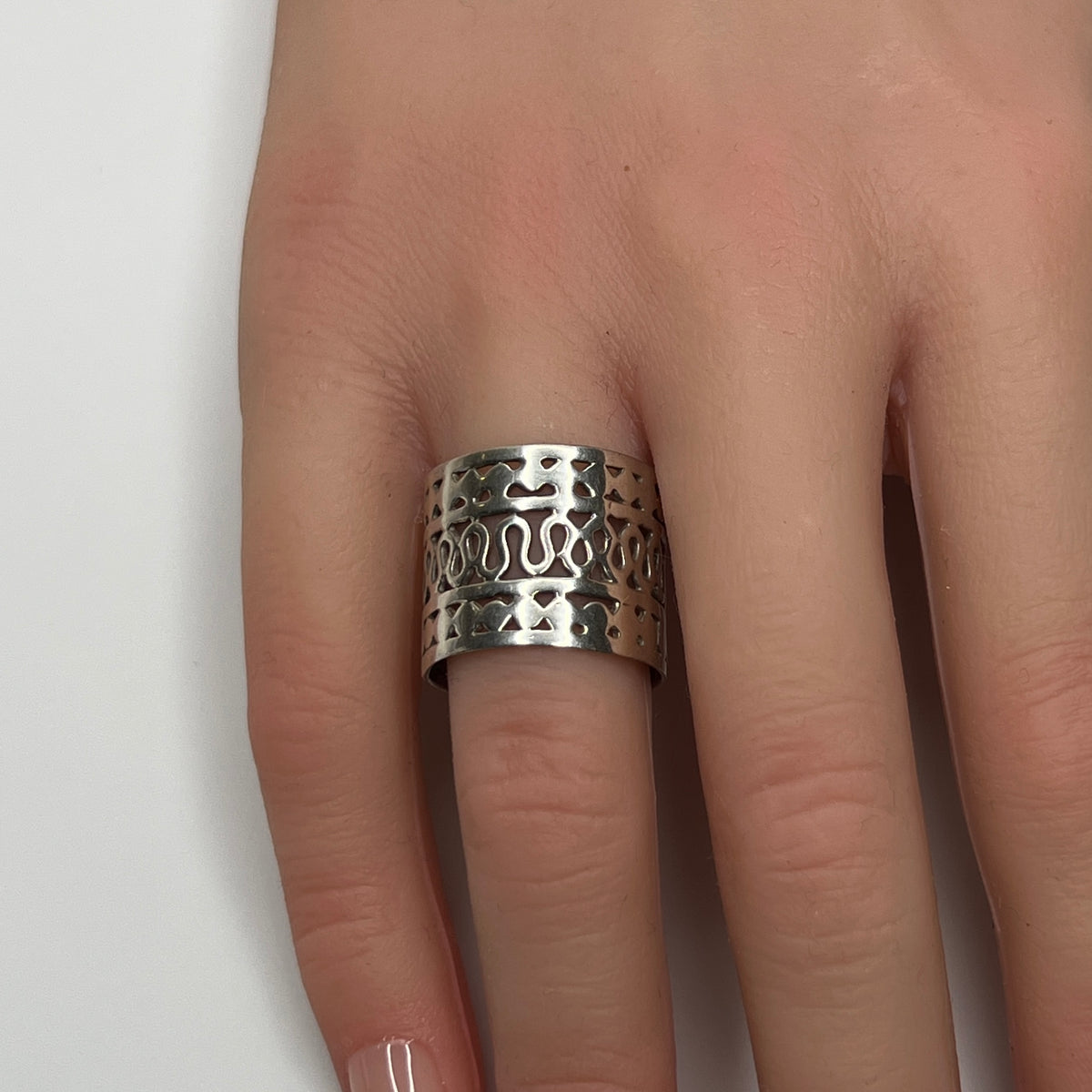 Sterling silver wide swirl cutout ring on hand, mid-century modern design