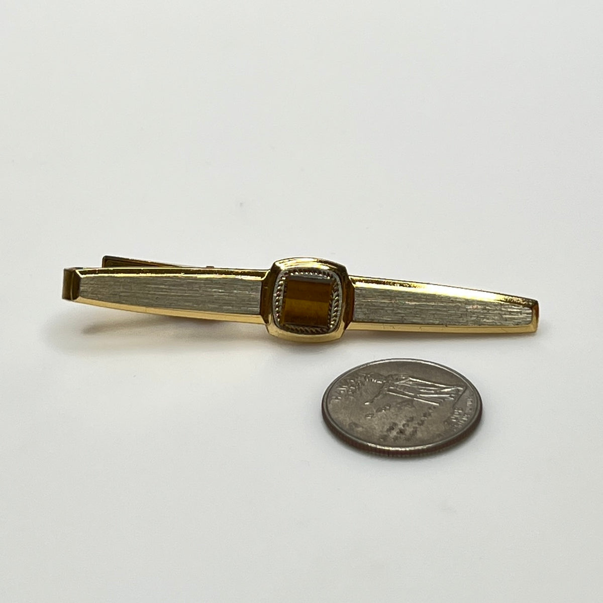 Close-up of goldtone tie bar with square tiger’s eye stone