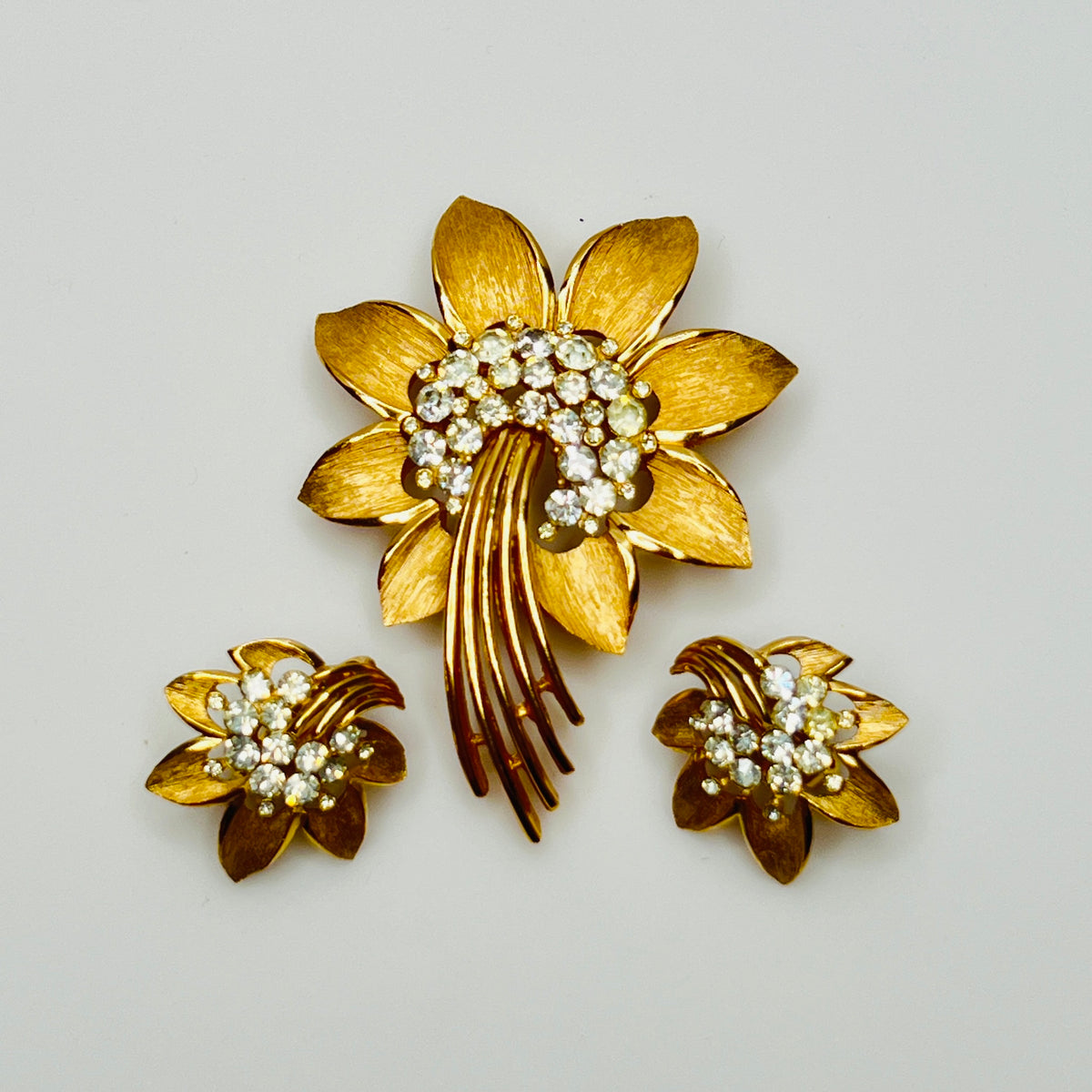 Trifari gold-tone floral brooch with matching clip-on earrings and rhinestone centers