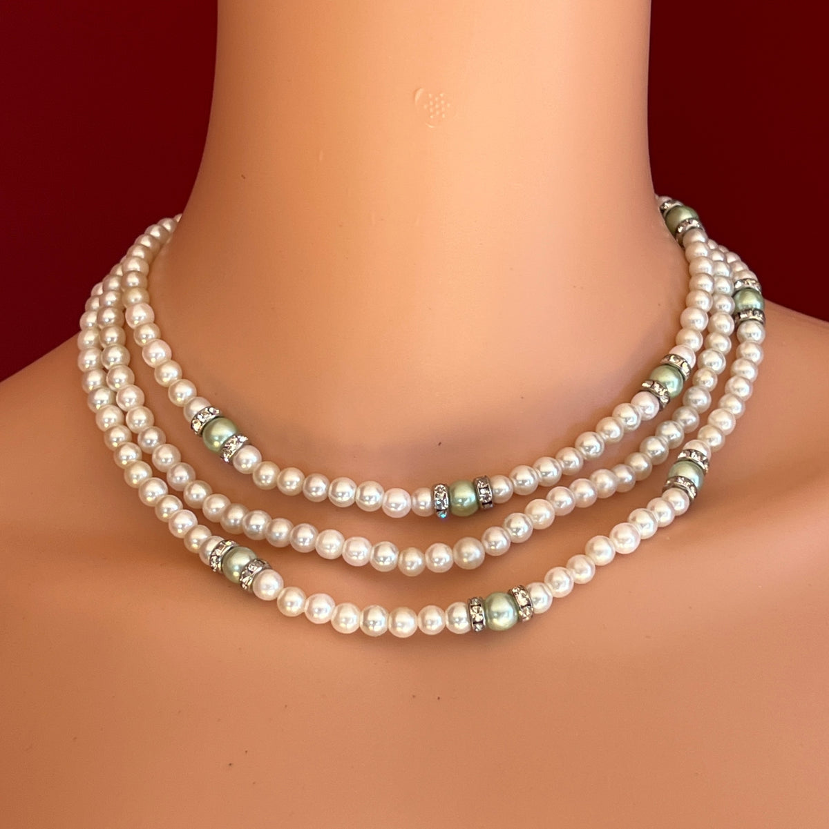 Three-strand faux pearl necklace and bracelet set with sage green pearls and rhinestone spacers.