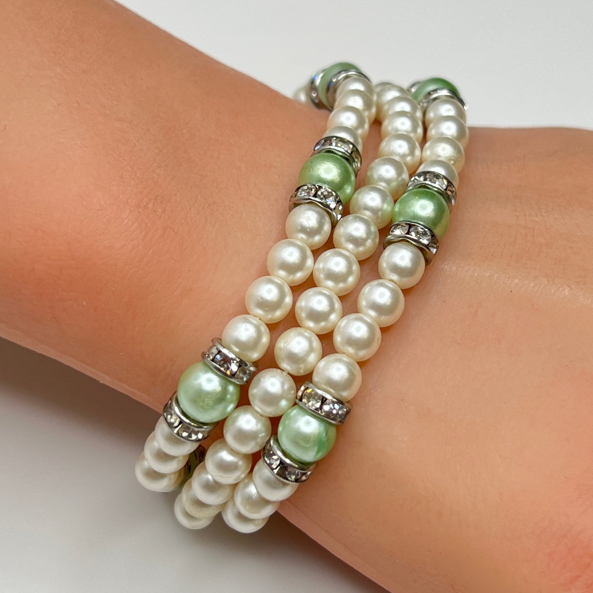 Three-strand faux pearl necklace and bracelet set with sage green pearls and rhinestone spacers.