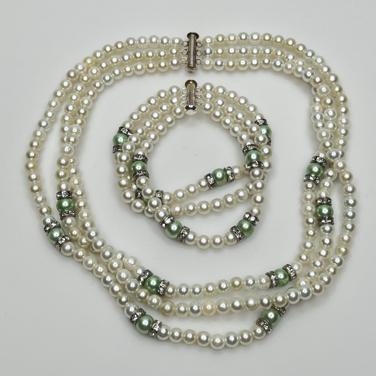 Three-strand faux pearl necklace and bracelet set with sage green pearls and rhinestone spacers.