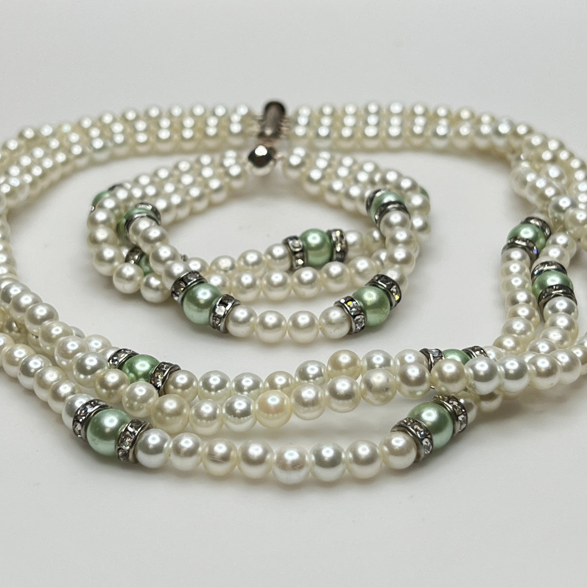 Three-strand faux pearl necklace and bracelet set with sage green pearls and rhinestone spacers.