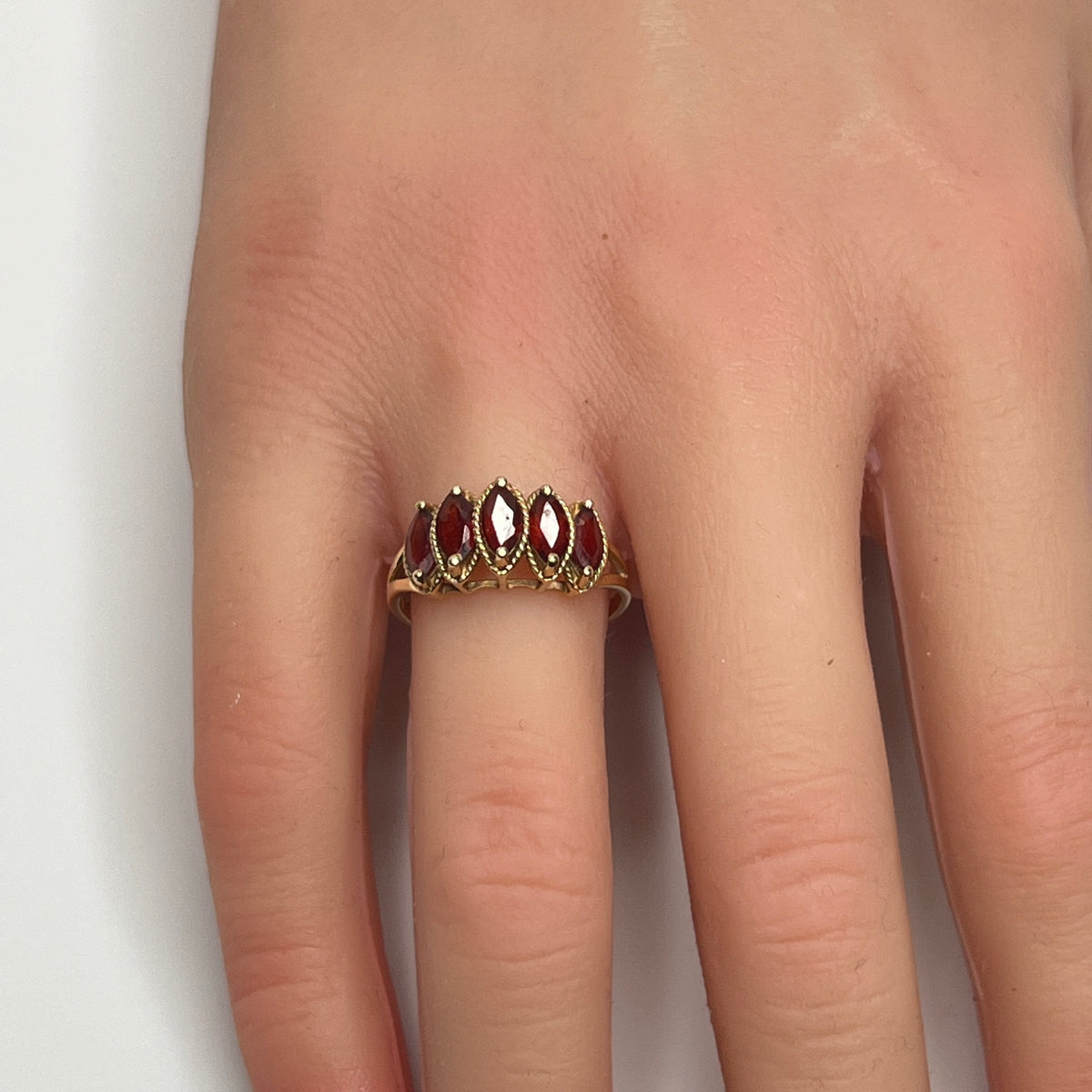 Vintage 10K gold ring with five marquise garnets on model’s hand