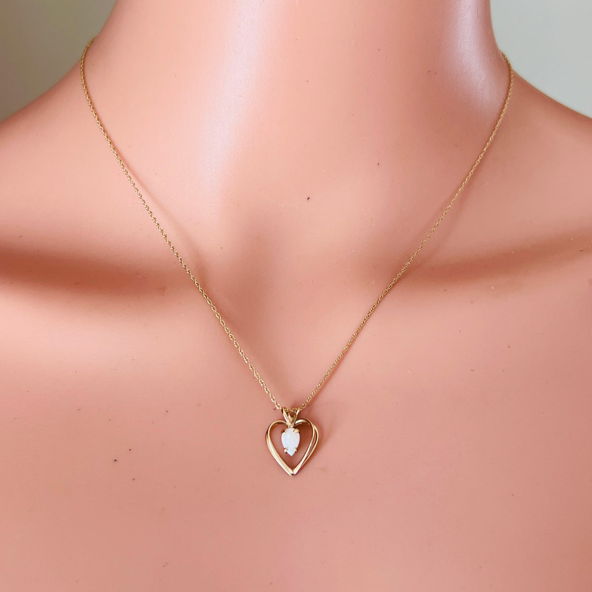 Opal heart necklace worn on mannequin minimalist gold jewelry