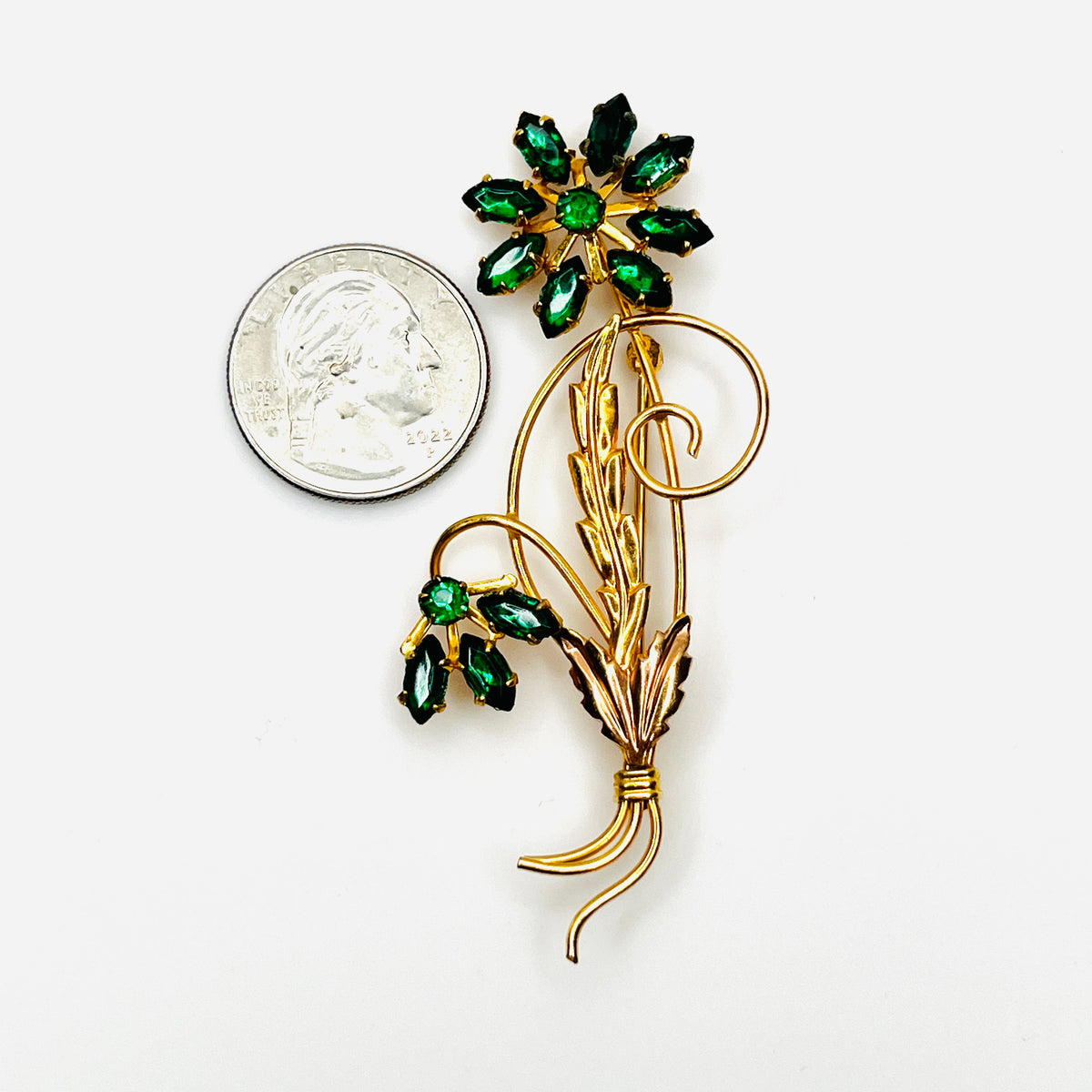 Michaelson & Sons green rhinestone flower brooch shown beside quarter for scale