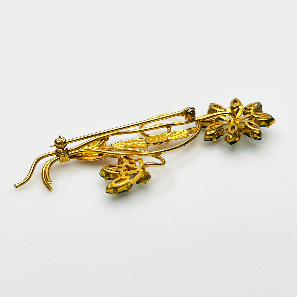 Side view of dimensional 12K gold filled floral brooch with green glass rhinestones
