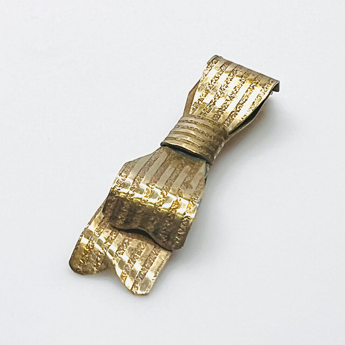 Side view of 1950s textured gold-tone bow pin showing layered ribbon loops and dimensional construction