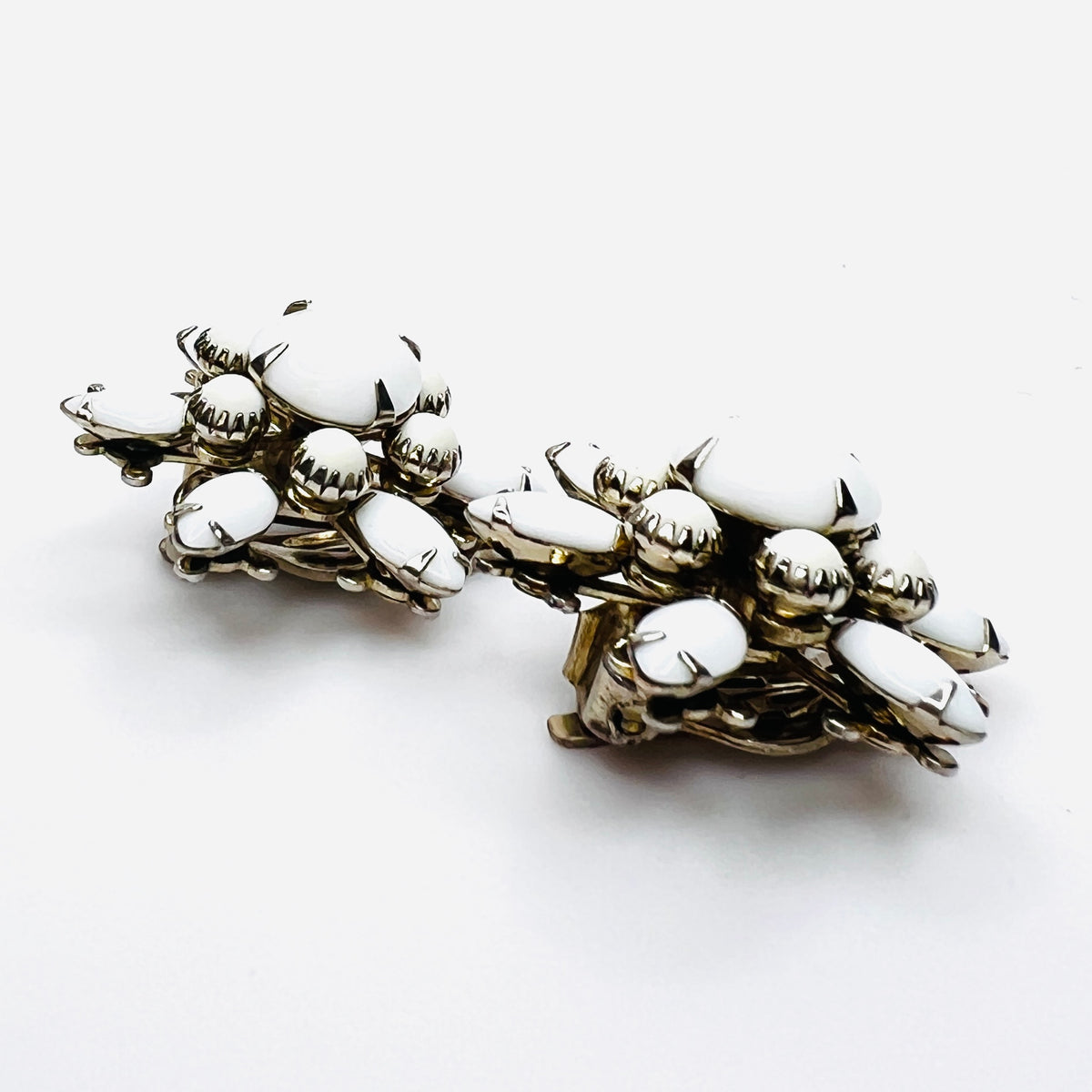 Side view of vintage milk glass flower clip-on earrings in silver-tone setting.