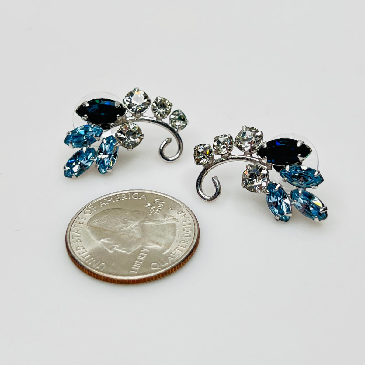 Mid-century blue and clear rhinestone earrings beside quarter for scale
