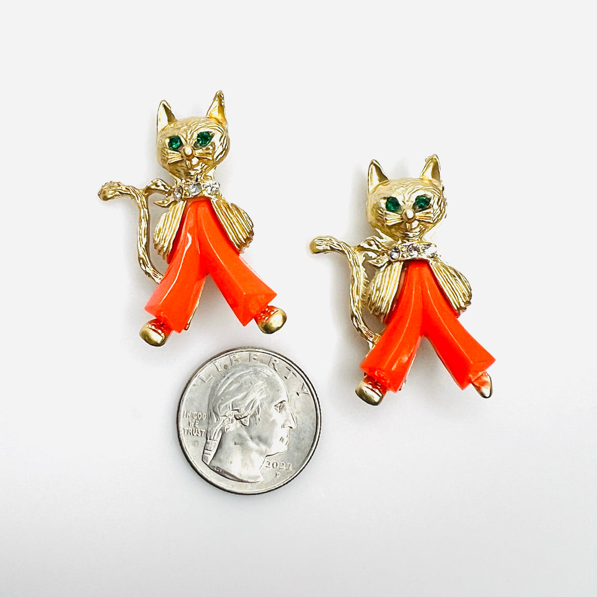 Vintage MCM cat brooch pair with coral Lucite trousers shown beside quarter for scale