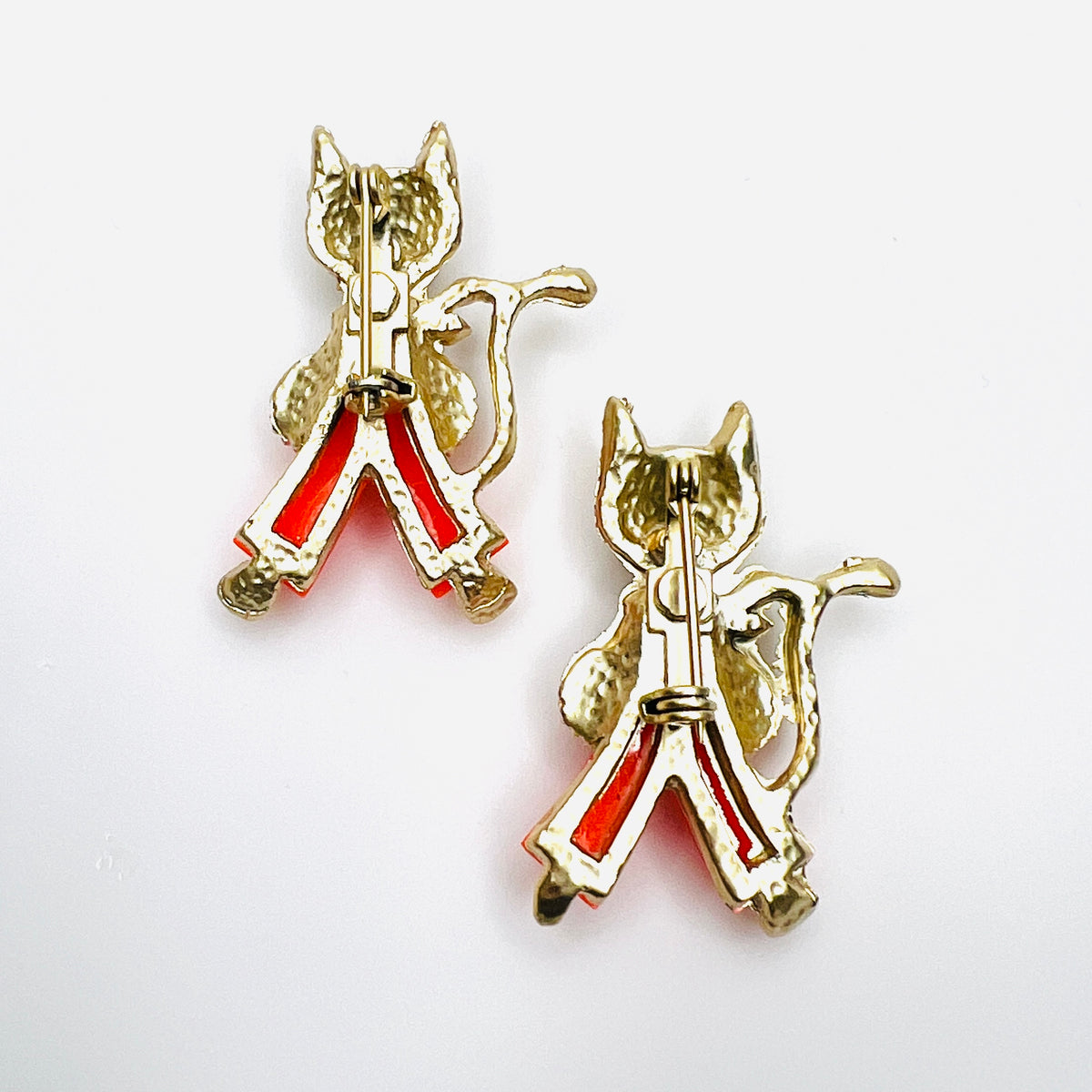 Reverse of vintage 1950s cat brooch pair showing gold-tone construction and individual pin backs